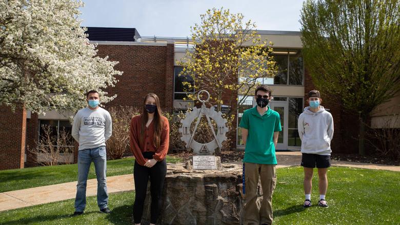 四个学生站在雕像旁边